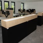 Moderne Büroeinrichtung mit Schreibtischen, Monitoren und ergonomischen Stühlen in heller Arbeitsumgebung