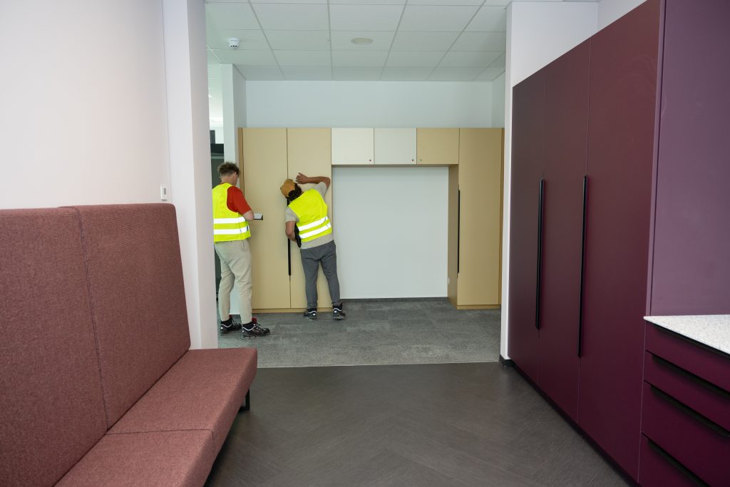 Aufbau von Büromöbeln in einem modernen Unternehmensflur mit professionellem Montageteam