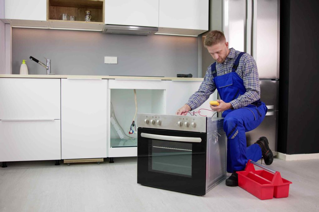 Monteur schließt Backofen in moderner Einbauküche an – Küchenmontage vom Profi
