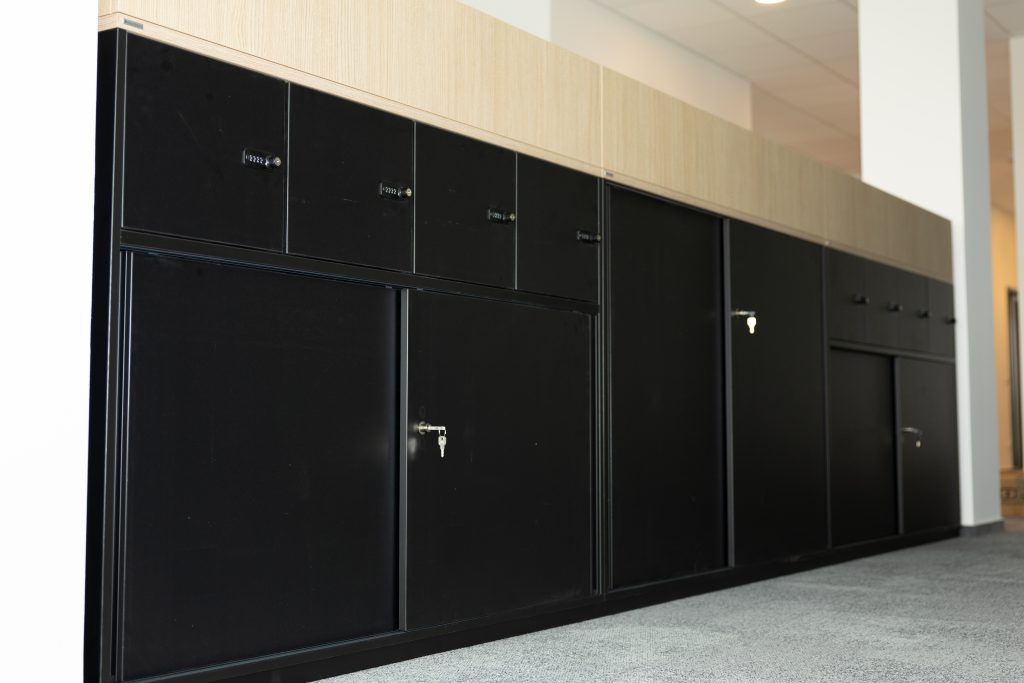 Schwarze Büro-Schranksysteme mit abschließbaren Schubladen und Holzaufsatz in moderner Arbeitsumgebung