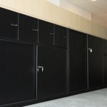 Schwarze Büro-Schranksysteme mit abschließbaren Schubladen und Holzaufsatz in moderner Arbeitsumgebung